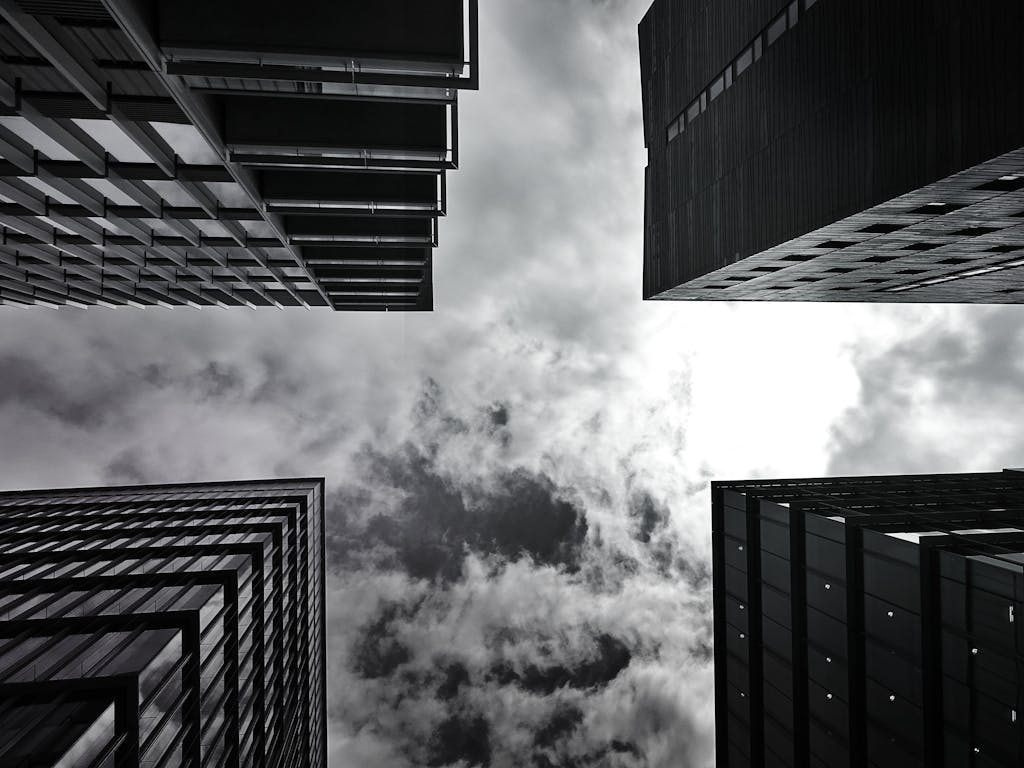 Low angle shot of tall skyscrapers and cloudy sky, captured in monochrome.